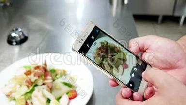 手机屏幕上的凯撒沙拉，厨师在餐厅的专业厨房里拍照食物，照片食物移动